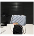 Close-up of light blue quilted crossbody bag with gold turn-lock and chain strap - Blue