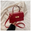 Detalle de bolso rojo con textura lichi, cierre giratorio dorado y bandolera - Rojo