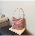 Detalle de bolso rosa con lazos plateados sobre un libro de arte en un ambiente moderno - Rosa