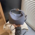 Bolso de hombro azul con textura tejida y cierre giratorio dorado en escena urbana - Azul