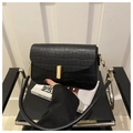 Detalle del bolso negro con patrón de cocodrilo y elegante cierre metálico dorado - Negro