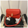 Detalle de bolso rojo con textura de cocodrilo, cierre dorado y correa de cadena - Rojo