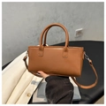 Detalle de un bolso de piel marrón con asas dobles y grabado de la palabra FASHION - Tostado