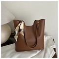 Close-up of brown leather tote bag with decorative silk scarf and fashion text logo - Tan