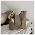 Close-up of khaki tote bag with a patterned silk scarf on the strap over a table - Khaki