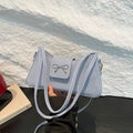 Elegant light blue woven shoulder bag featuring a silver bow buckle and slim strap - Blue