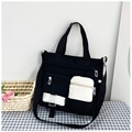Dettaglio della borsa tote in tela a contrasto con tasche bianche e tracolla regolabile - Nero