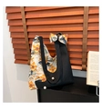 Dettaglio borsa tote floreale con accenti di perle e ciondolo a fiocco su rack - Nero
