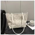 Detailed macro view of 3D embossed floral texture on a cream white leather tote bag - White