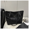 Detailed macro view of embossed plum blossom pattern and golden logo on black tote bag - Black