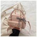 Close-up of pink PU leather shell bag with bow detail and plaid ribbon on handle - Pink