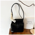 Detail of black textured leather shoulder bag with delicate white lace bow accessory - Black