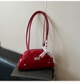Primer plano del bolso de hombro en charol rojo con lazo de encaje blanco y cremallera plateada - Rojo