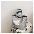 Minimalist silver metallic tote bag with thin straps on white suitcase for travel - Coffee