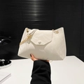 Weiße minimalistische Umhängetasche mit Crinkle-Struktur und goldener Kette in der Hand - Weiß