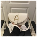 Detalle de un bolso de silla crema con hebilla dorada sobre una silla negra chic - Blanco