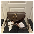 Detail of dark brown leather saddle bag featuring a large gold D-shaped metal buckle - Coffee