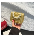 Close-up of golden heart quilted handbag featuring pearl handle and gold chain strap - Gold