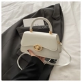 Detailed macro view of the cream leather handbag with gold V-shaped metal lock closure - White