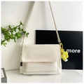 Detail of cream nylon crossbody bag featuring large flap and yellow flower charm accent - Rice White (With Pendant)