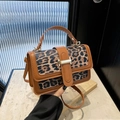Detail of leopard print handbag featuring brown leather trim and golden metal clasp buckle - Brown