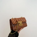 Dettaglio borsa a tracolla trapuntata color mogano con fibbia dorata e tracolla a catena - Marrone