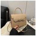 Detail of beige faux leather handbag featuring a circular metal twist lock and top handle - Khaki