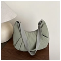 Dettaglio della borsa a mezzaluna in nylon verde salvia su un tavolo di legno - Verde