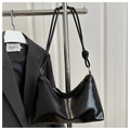 Detail of black glossy leather tote featuring a knotted strap design and metal hardware - Black