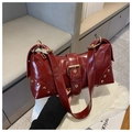 Detail der dunkelroten Lackledertasche mit goldenen Nieten und Schnallenriemen - Rot