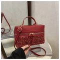 Bolso tipo caja de tweed rojo con herrajes dorados y cuero en un entorno cálido - Rojo