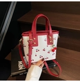 Detailansicht der weißen Beuteltasche mit Kirschmuster und roten Lederriemen - Rot mit Anhänger