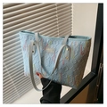 Detail of light blue tote bag featuring wave embroidery and leather logo brand tag - Blue