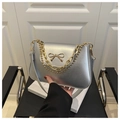 Detail of silver metallic bag featuring a gold bow buckle and elegant dual chain straps - Silver