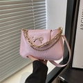 Bolso de hombro de cuero rosa con lazo dorado y correa de cadena metálica en escena de moda - Rosa