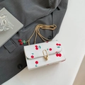 White leather chain bag with red cherry print and golden oval metal lock detail - White