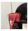 Close-up of red lychee pattern leather handbag with metal buckle and wide shoulder strap - Red