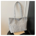 Detalle de bolso tote plateado con remaches dorados y textura de cuero charol arrugado - Gris