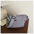 Detail of gray nylon crossbody bag with adjustable strap on a wooden table setup - Gray