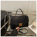 Detalle del bolso de cuero negro con textura de cocodrilo y cierre de hebilla dorada - Negro