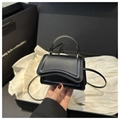 Dettaglio macro della mini borsa nera con base ondulata tenuta in mano come accessorio - Nero