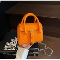 Close-up of mini orange faux leather handbag with silver chain strap and buckle detail - Orange