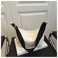 Detail of white hobo bag showing zipper closure and black nylon strap on art book - White