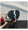 Detail view of heart-shaped black leather bag with white lightning print and silver hardware - Black