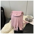 Detailed macro of pink pebbled leather crossbody bag featuring bohemian long tassels - Pink