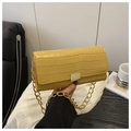 Detailed shot of yellow crocodile texture leather bag with a bold gold chain handle - Yellow