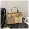 Detail van de tote bag met krokodillenprint en goudkleurige sluiting op zwarte houten tafel - Khaki