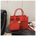 Detail van rode krokodillentextuur op stijlvolle kunstlederen tote met gouden slot - Rood