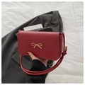 Schicke rote Schultertasche mit goldener Schleife auf grauem Blazer, minimalistisch - Rot