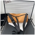 Detail van een heldergele cilindrische tas met zwarte nylon banden en een zicht op de rits - Groot Geelbruin